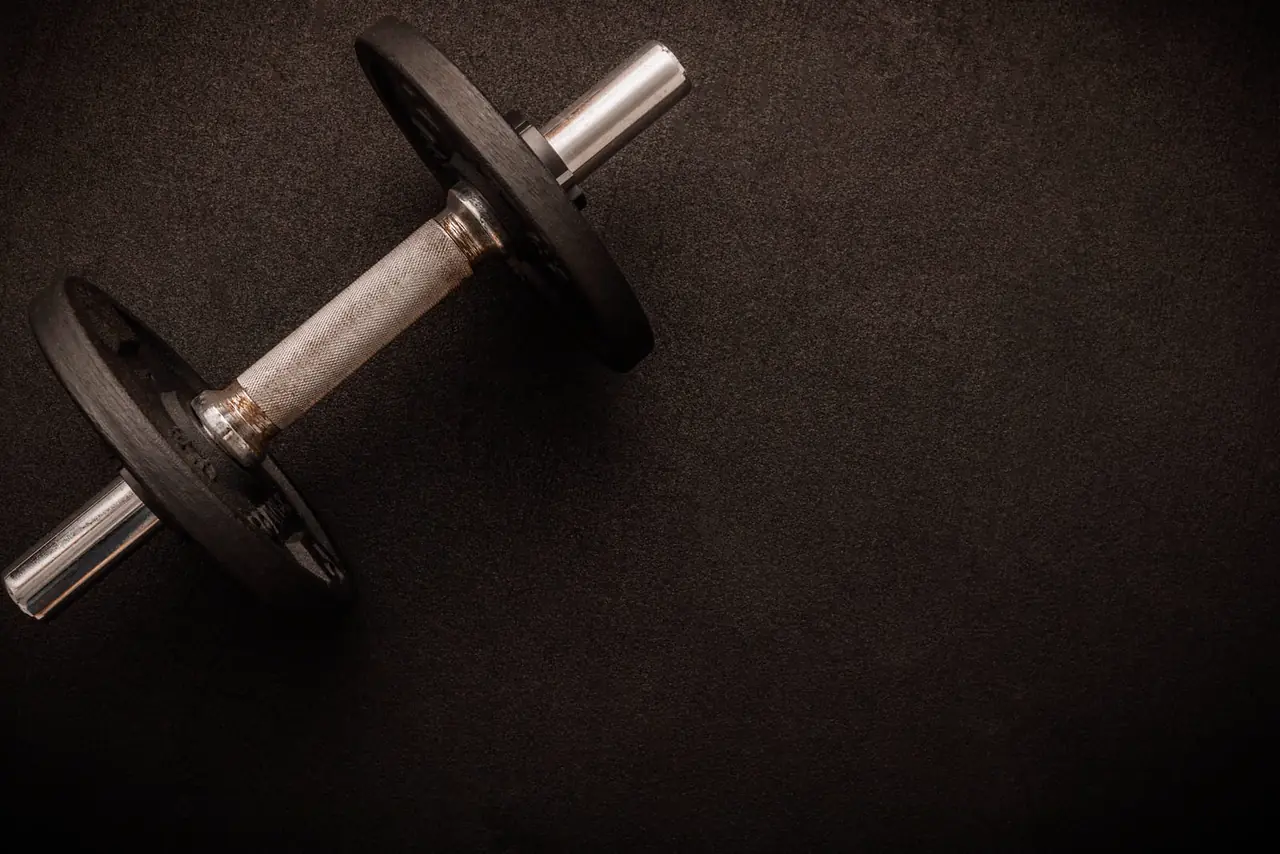 A dumbbell on a dark gym floor.